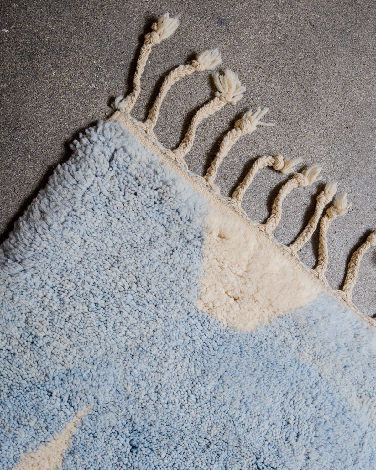 Corner of rug made of thick wool pile and natural wool tassels.